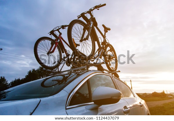 Bike transportation - two bikes on the roof of a car
against a beautiful sky. the end of the transportation of large
loads and travel by car