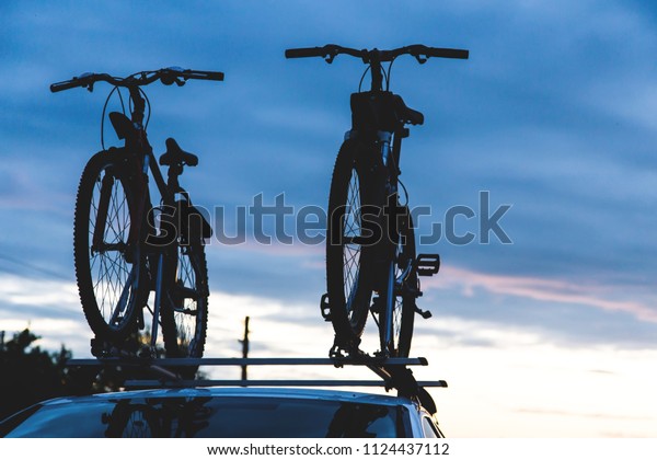 Bike transportation - two bikes on the roof of a car
against a beautiful sky. the end of the transportation of large
loads and travel by car