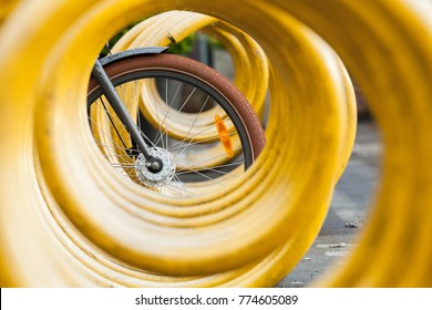 Bike wheel and yellow spiral bicycle parking lot stand