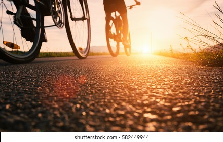 Bike wheels close up image on asphalt sunset road