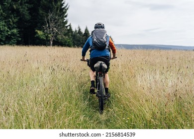 Bikepacking in the mountains. Man standing on a meadow with his bike and backpack ready for a bikepacking adventure ride.