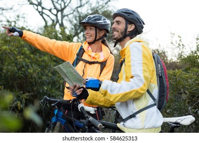 Biker couple with a map pointing in distance at countryside - Powered by Shutterstock