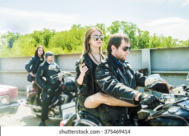 Biker Couple With Motorcycle Chopper Style Man And Woman Ride With High Speed Cute Girl Wear Black Leather Jacket And Stylish Sunglasses Against Urban Background Gang Of Groups Of Armed People