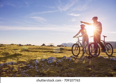 Biker couple with mountain bike pointing in distance at countryside - Powered by Shutterstock