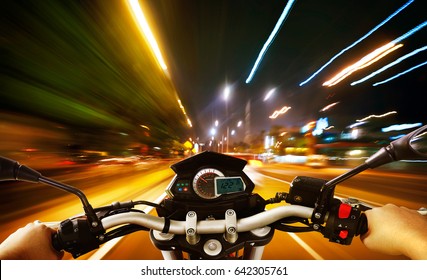 Biker Driving A Motorcycle Rides Along The City Street , Night Scene . First Person Angle View .