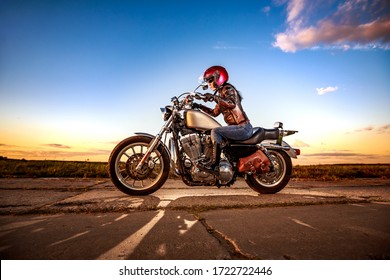 Bikermädchen in Lederjacke und Helm auf dem Motorrad