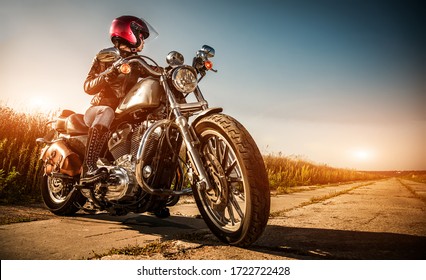 Une fille en vélo sur une moto avec une veste en cuir et un casque, regarde la route