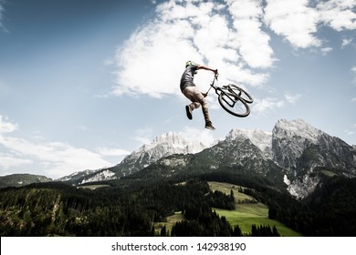 biker jumps a high stunt with mountains in the back - Powered by Shutterstock