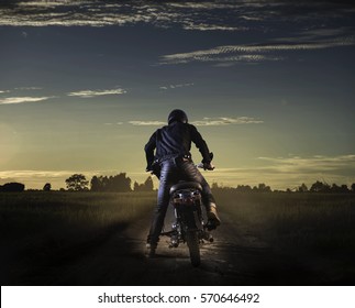 Biker Kick Start Vintage Motorcycle On Country Road.