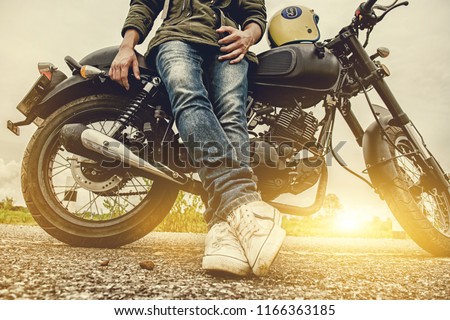 Biker man with his motorbike(motorcycle) on street and beautiful, enjoying freedom and active lifestyle, having fun on a bikers tour.