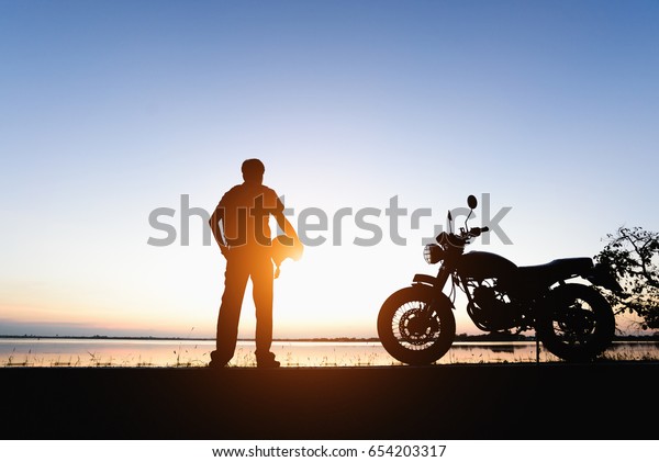 バイカーの男性とバイクの若い乗り手は 旅の間に 自然の光 夜間の空