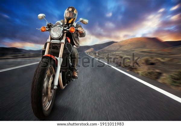a biker on a motorcycle rides on an asphalt\
road in the mountains