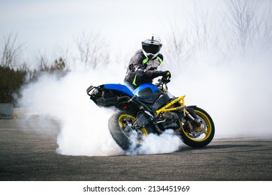 Biker performing a burnout with his stunt motorcycle and creating a lot of smoke from the rear wheel