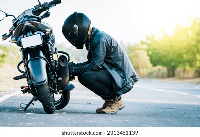 Reparando motocicleta en la carretera. Motociclista arreglando la motocicleta en la carretera, hombre revisando su motocicleta en la carretera
