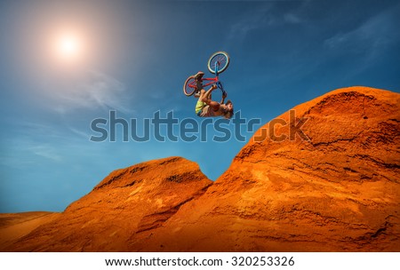 Biker rides on road in the high mountains of sand dunes . Background blue sky with clouds