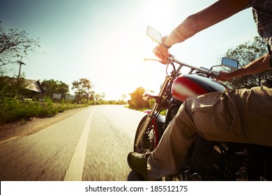 Biker Riding Motorcycle  On An Empty Road At Sunny Day