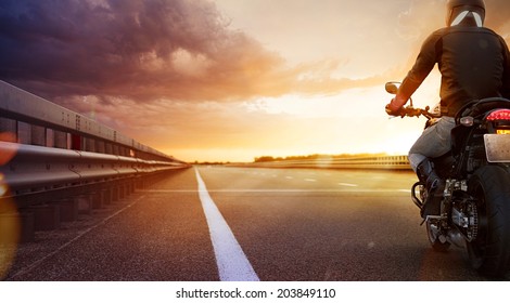 Biker Riding Motorcycle On An Empty Road At Sunset