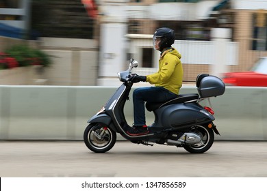  An Biker Riding Vespa Is An Italian Brand Of Scooter In City Traffic With Blur Background In Hong Kong On 24 Mar 2019