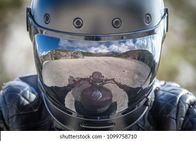 Le cycliste reste sur sa moto avec un paysage de montagne désolé reflété sur son viseur de casque