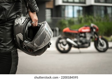 Biker walks to motorcycle holding helmet in hand - Shutterstock ID 2200184595