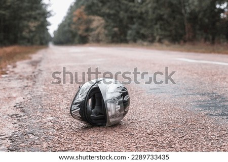 A biker's helmet lies on the road. A motorcycle helmet is lying on a wet street. The concept of a traffic accident, an accident with a motorcycle.