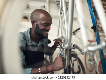 Bikes are my passion. Shot of a handsome young man crouching in his shop and repairing a bicycle wheel.