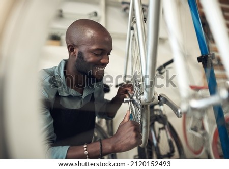 Bikes are my passion. Shot of a handsome young man crouching in his shop and repairing a bicycle wheel.