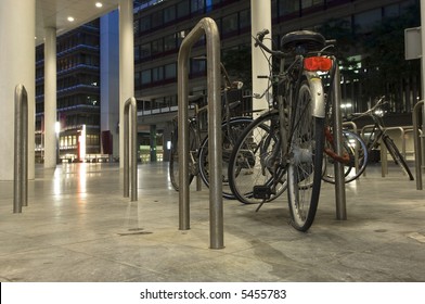 Bikes Parked Outside One Of The Ministries In The Hague, The Netherlands At Night, One With A Flat Tire