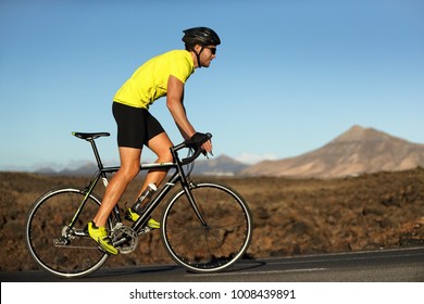 Biking Cyclist Male Athlete Going Uphill On Open Road Training Hard On Bicycle Outdoors At Sunset. Nature Landscape.