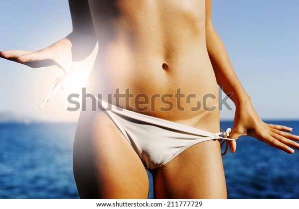  Bikini\
line against dark tanned skin, white bikini, sea in the background,\
hands stretching, muscular\
abdomen