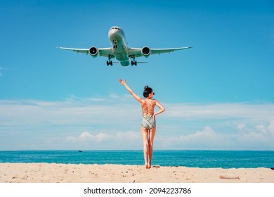 Bikini women watching airplane landing on Mai Khao Beach, Phuket province, Southern of Thailand