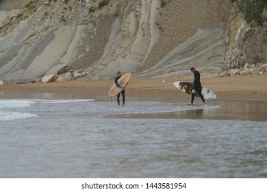 Bilbao, SALVAJE Beach / Spain - June 8, 2019: Surfer Waiting Wave. Water Splashes Before Young Surfers Waiting For Epic Barrel Wave. Extreme Young Pro Sportsmans Going To Wave In Cloudy Summer Sunset