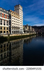 BILBAO, SPAIN - FEBRUARY 14, 2022: Ribera Del Nervión Area With The Bailen Skyscraper And The La Concordia Railway Station Reflected On The Water In The City Of Bilbao , Basque Country, Spain.