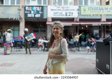 Bilbao, Spain - Jul. 23, 2022: A Woman Spectator, With Gray Hair, Enjoys The Folk Fusion Music Of The Group Kuttune, During A Concert At The Local Festivities In Echevarri