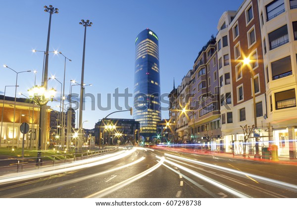 BILBAO, SPAIN - MARCH 24, 2017: The Iberdrola\
tower at sunset. It\'s the highest building on the Basque country,\
Spain. Photo taken from Elcano street, with the light trails of the\
traffic.