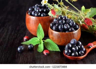 Bilberries in wooden bowls against the dark background