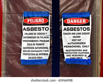 Bilingual asbestos warning signs on plastic covering a front door