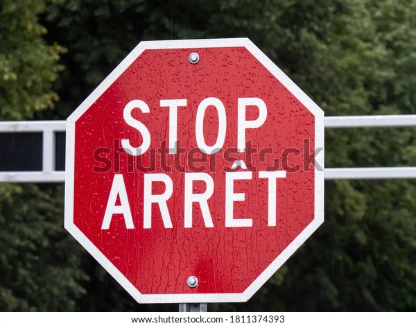 A\
bilingual English and French stop sign on a\
gate