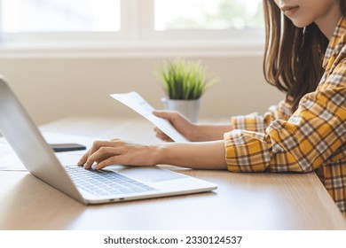 Bill pay concept. Online internet banking asian young woman work at desk on laptop computer at home, female calculate finance, hand holding paperwork, bills tax for payment. Technology of financial. - Shutterstock ID 2330124537