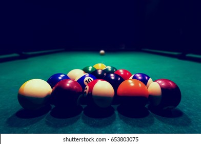 Billards pool game. Color balls in triangle, aiming at cue ball. black night background