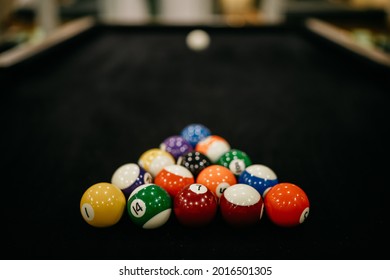 Billards pool game. Colored balls in a triangle aimed at a white sphere. Dark linen table. Billiard balls on table