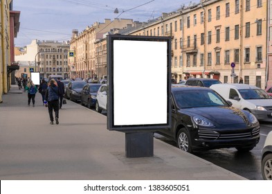 Billboard On The Streets. Vertical Billboard Advertising On The Background Of The City And Cars Parked On The Side Of The Road. Porsche Mockup  