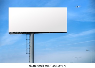 Billboard outdoor advertising, mockup billing board in front of a blue sky with a flying plane near the airport. Blank white background for branding design large hoarding - Shutterstock ID 2061669875