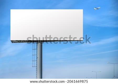 Billboard outdoor advertising, mockup billing board in front of a blue sky with a flying plane near the airport. Blank white background for branding design large hoarding