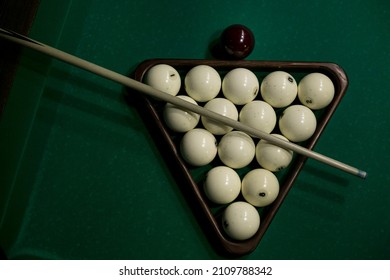 billiard balls, cues and cue ball lie on the game green table. top view, background