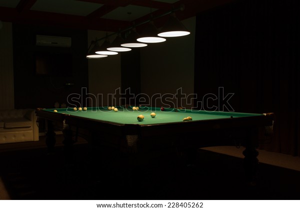 Billiard Balls Scattered on Pool Table in Empty\
Dimly Lit Pool Hall