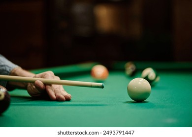 Billiard cue in hands of young male player standing by pool table and concentrating before hitting white ball during game - Powered by Shutterstock