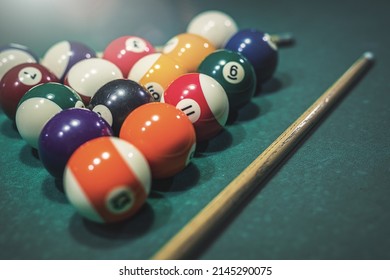 billiard cue and a pyramid of colorful balls on a green pool table. Billiards concept