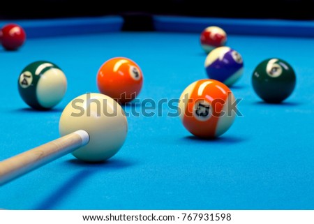 Billiard pool eightball taking the shot on billiard table with blue cloth, selective focus on white ball