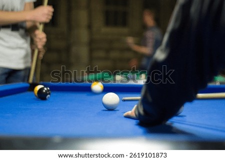 Billiard pool game in progress, player aims to shoot balls with cue